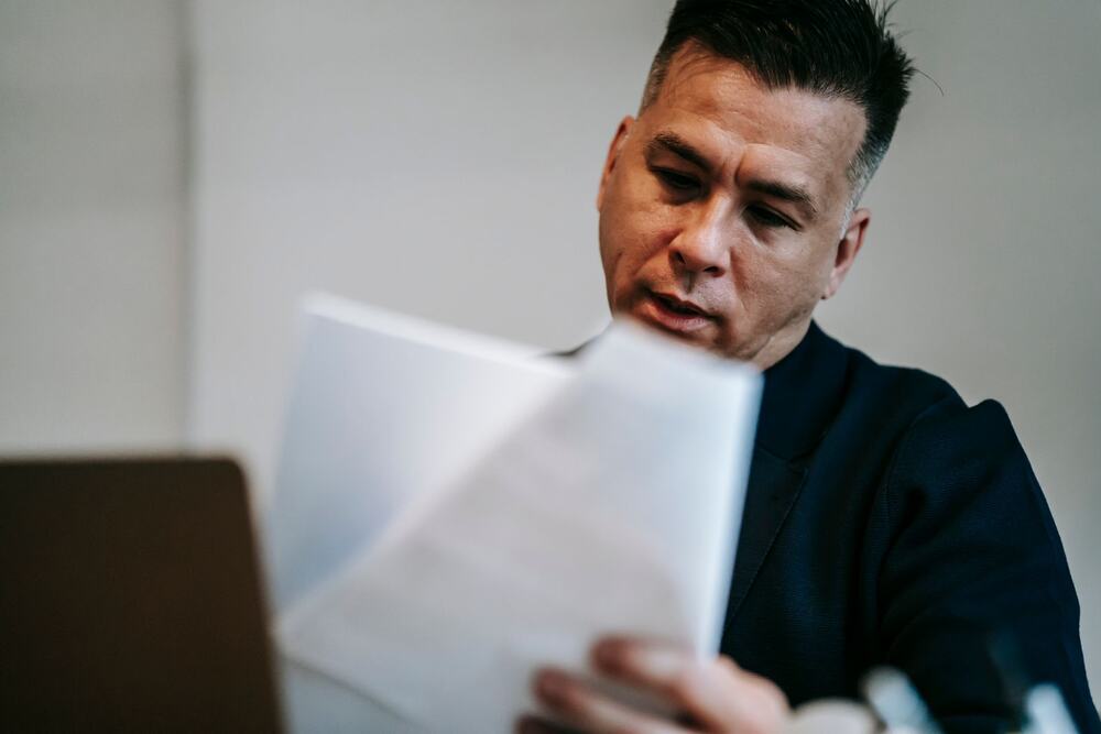 Professional reviewing paperwork at a desk (representative stock photo)